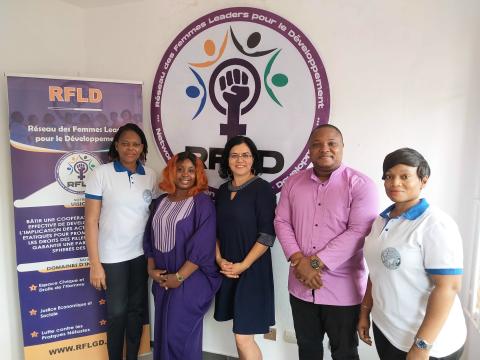 Photo of Gabriella standing with other staff from RFLD in front of the organization logo