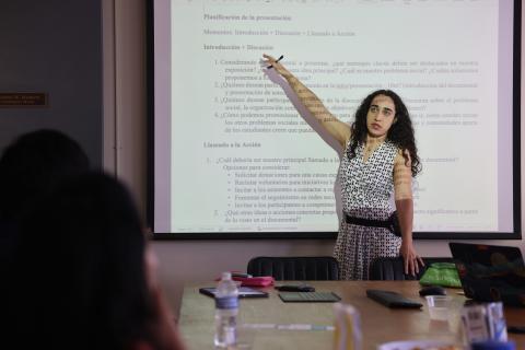 Larissa standing in front of a projector, speaking to a group.