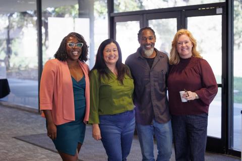 A group of four students stand together, smiling at the camera.