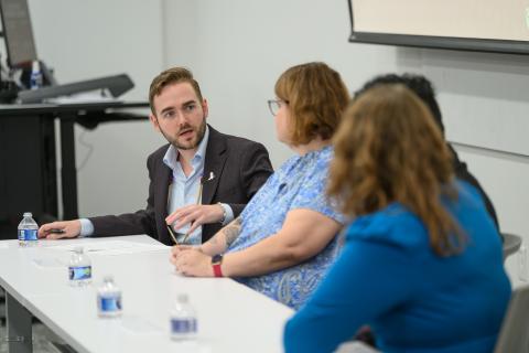 Photo of the panelists speaking with student Evan Wolstencroft