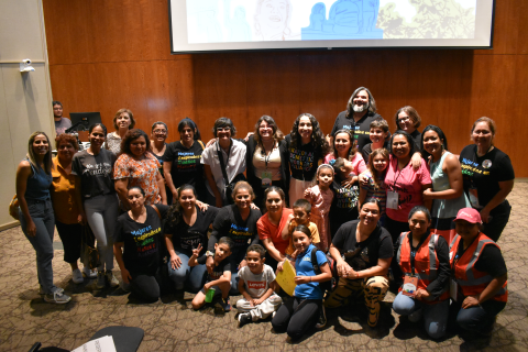 A group of guest speakers, organizers, and attendees standing in Bass Lecture Hall, smiling.