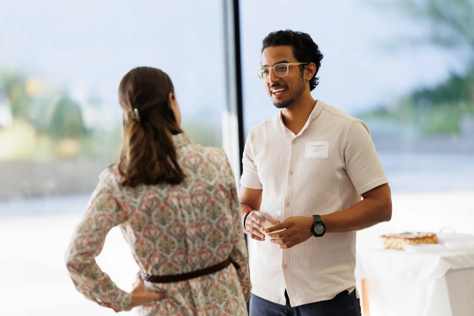 Student smiling at an event, talking with a staff member