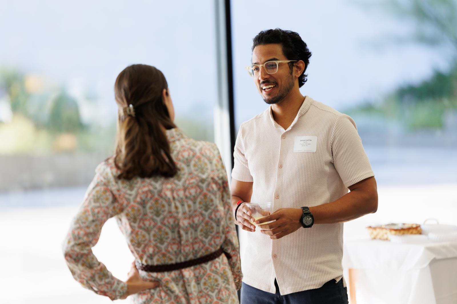 Student smiling at an event, talking with a staff member
