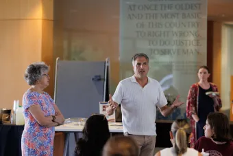 Noel and Sarah Jane standing in front of a group of students, talking.