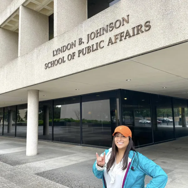 Fernanda in front of the LBJ School of Public Affairs throwing up a Hook 'Em!